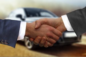 shaking hands after purchasing a used luxury car